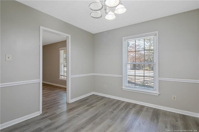 spare room featuring wood finished floors, baseboards, and a wealth of natural light