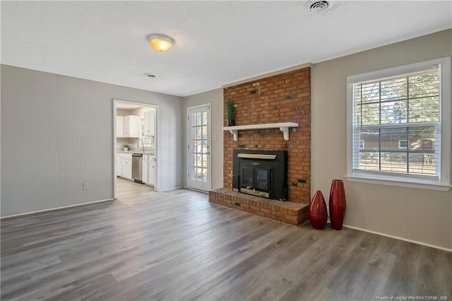 unfurnished living room with visible vents, a healthy amount of sunlight, and light wood-type flooring