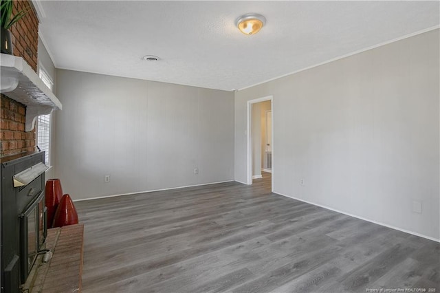 unfurnished living room with wood finished floors, visible vents, and ornamental molding