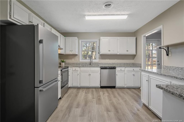 kitchen featuring stainless steel appliances, plenty of natural light, visible vents, and white cabinets