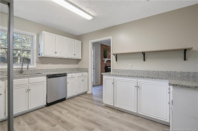 kitchen featuring a sink, light wood-type flooring, stainless steel dishwasher, and white cabinets