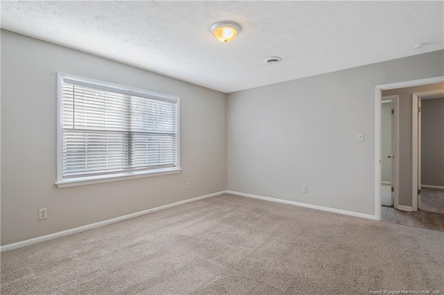 carpeted spare room featuring baseboards, visible vents, and a textured ceiling