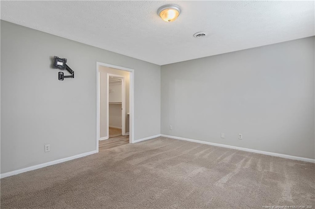 carpeted empty room with visible vents, a textured ceiling, and baseboards