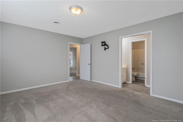 unfurnished bedroom with visible vents, carpet, baseboards, and ensuite bathroom