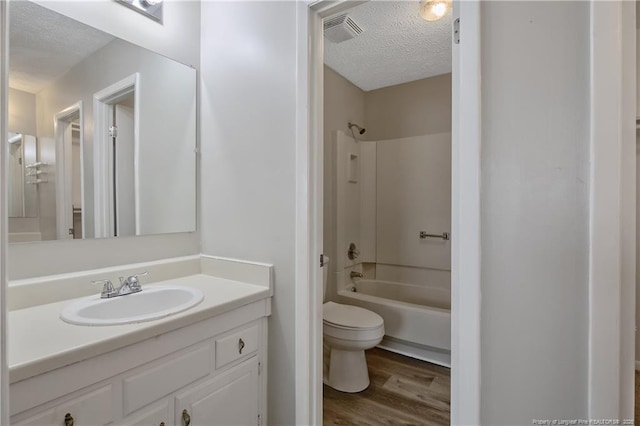 full bathroom featuring visible vents, toilet, a textured ceiling, wood finished floors, and shower / bathtub combination