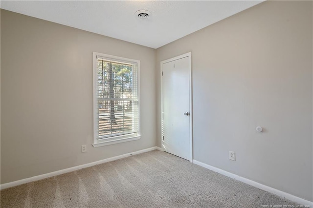 empty room with visible vents, light carpet, and baseboards