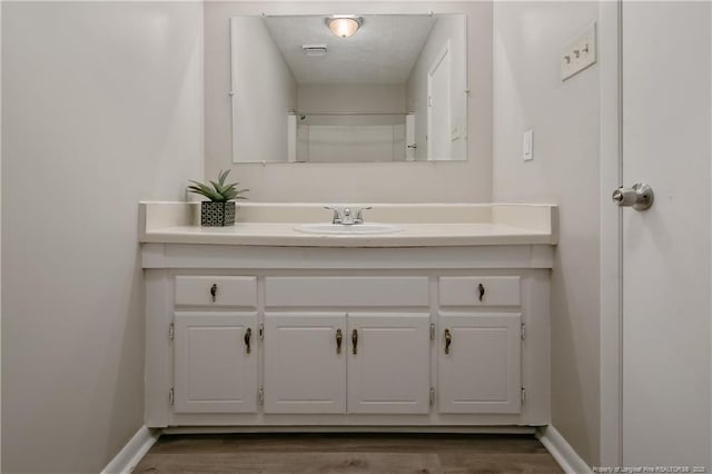 bathroom with vanity, baseboards, and wood finished floors