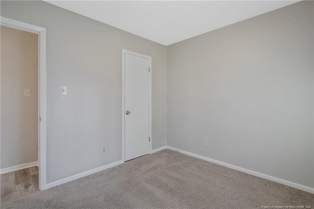 carpeted spare room featuring baseboards