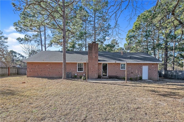 rear view of property featuring cooling unit, brick siding, a fenced backyard, and a chimney