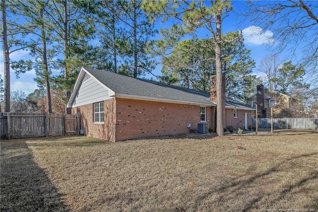 view of property exterior featuring brick siding, a yard, and fence