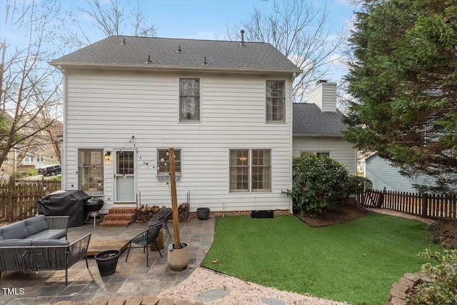 rear view of house with fence, entry steps, a lawn, a chimney, and a patio