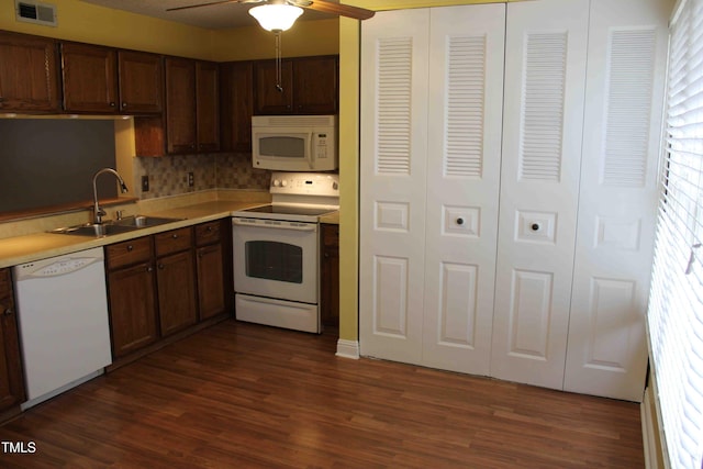 kitchen with dark wood-style flooring, white appliances, visible vents, and a sink