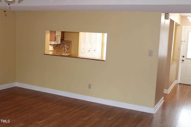 unfurnished room featuring dark wood-style floors and baseboards