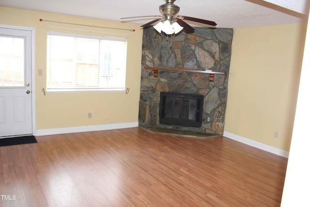 unfurnished living room with a ceiling fan, wood finished floors, a fireplace, and baseboards