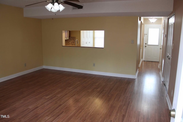 spare room with baseboards, dark wood-type flooring, and a ceiling fan