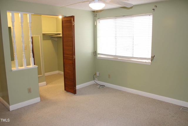 unfurnished bedroom with a ceiling fan, carpet, baseboards, a spacious closet, and a closet