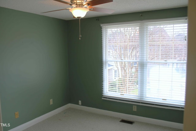 carpeted empty room featuring visible vents, a textured ceiling, a ceiling fan, and baseboards