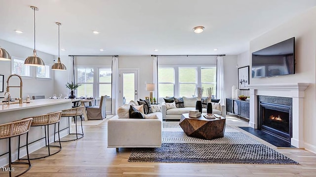 living area featuring recessed lighting, a healthy amount of sunlight, light wood finished floors, and a premium fireplace