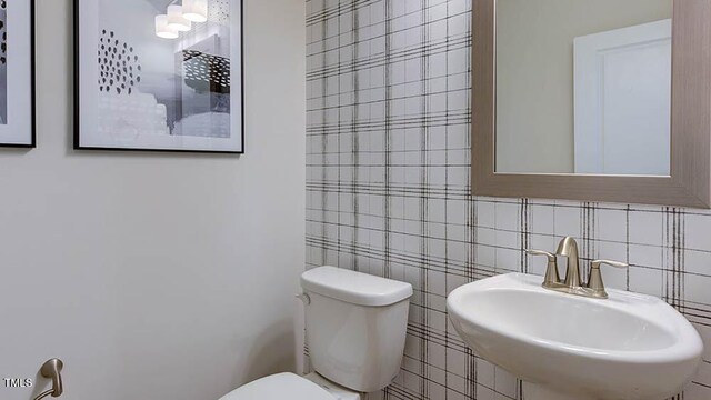 bathroom with backsplash, toilet, tile walls, and a sink