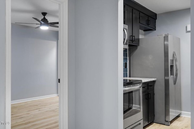 kitchen featuring dark cabinetry, a ceiling fan, light wood-style flooring, stainless steel appliances, and light countertops