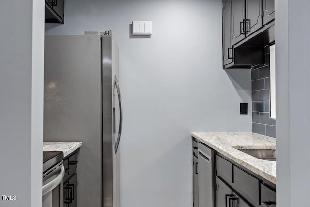 kitchen with light stone counters, appliances with stainless steel finishes, and a sink