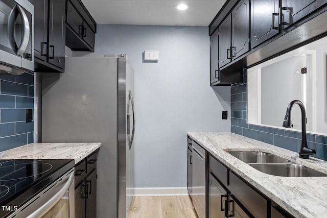 kitchen with light wood finished floors, decorative backsplash, stainless steel appliances, and a sink