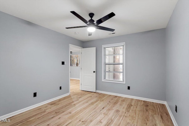 spare room featuring visible vents, a ceiling fan, baseboards, and wood finished floors