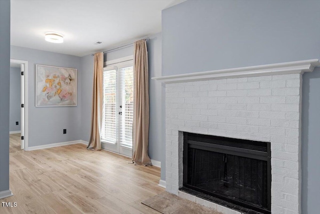 interior space featuring light wood-type flooring, baseboards, and a fireplace