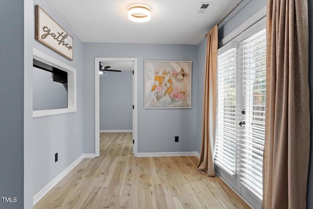 hallway with visible vents, baseboards, and wood finished floors