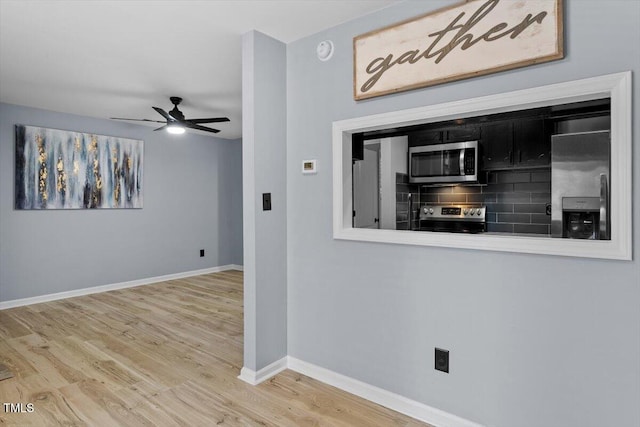 kitchen with wood finished floors, baseboards, ceiling fan, stainless steel appliances, and dark cabinets