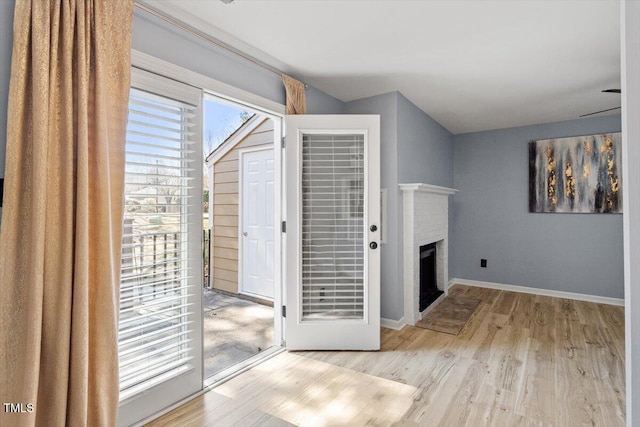 interior space featuring a fireplace, wood finished floors, and baseboards