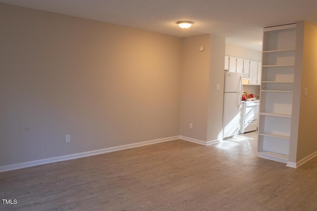 unfurnished room with baseboards and wood finished floors