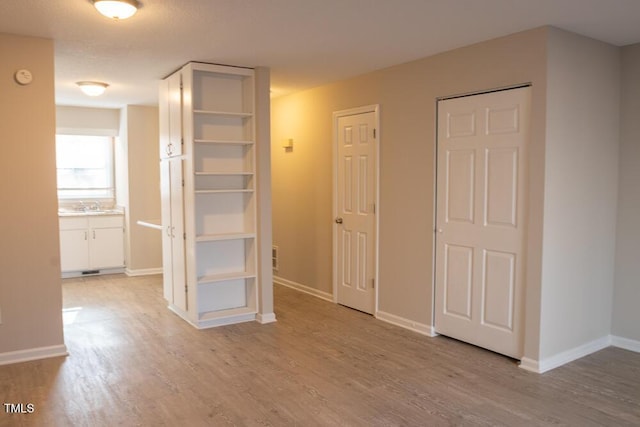 interior space with a sink, baseboards, and light wood-style floors