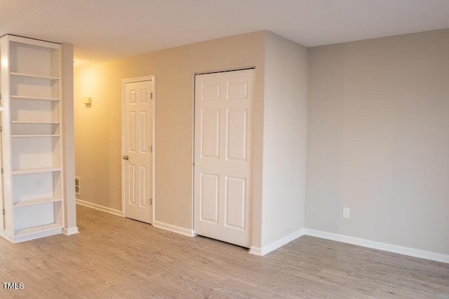 unfurnished bedroom with visible vents, baseboards, and wood finished floors