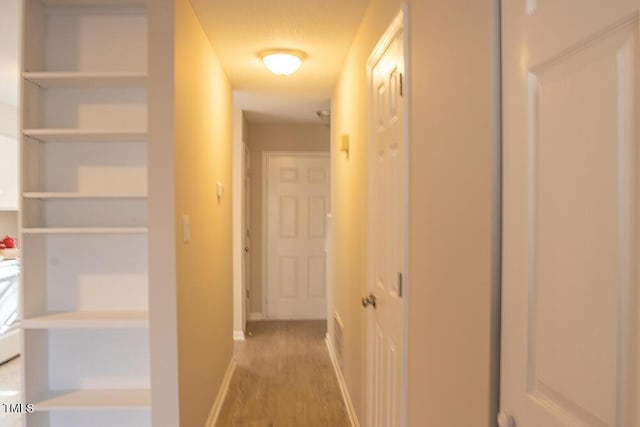 hall with light wood finished floors and baseboards