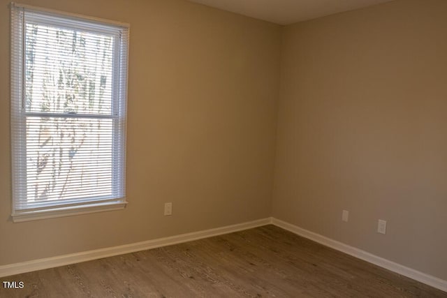 unfurnished room with baseboards and wood finished floors