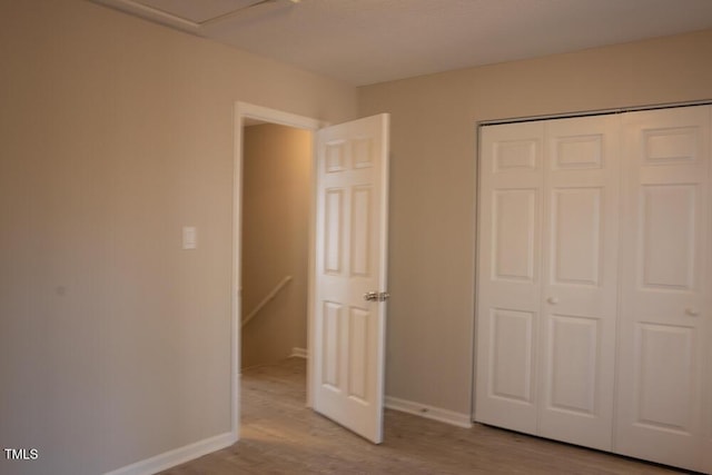 unfurnished bedroom featuring a closet, baseboards, and wood finished floors