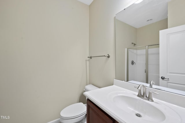 bathroom with vanity, toilet, baseboards, and a shower with shower door