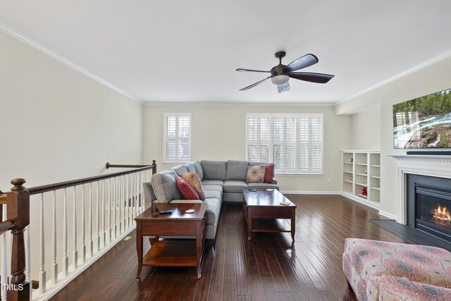 living room featuring a fireplace with flush hearth, dark wood finished floors, a ceiling fan, and ornamental molding