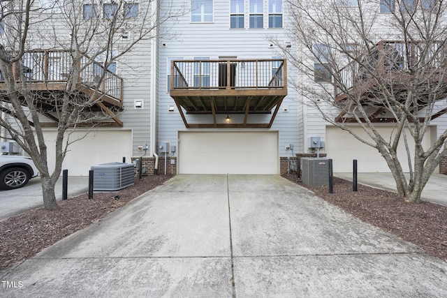 exterior space with concrete driveway, an attached garage, and central AC unit