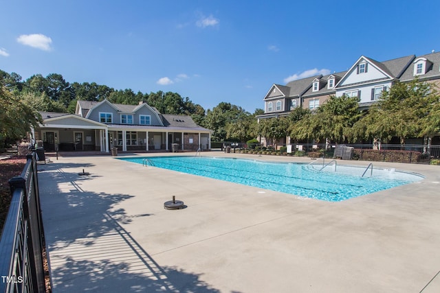 community pool with a patio and fence