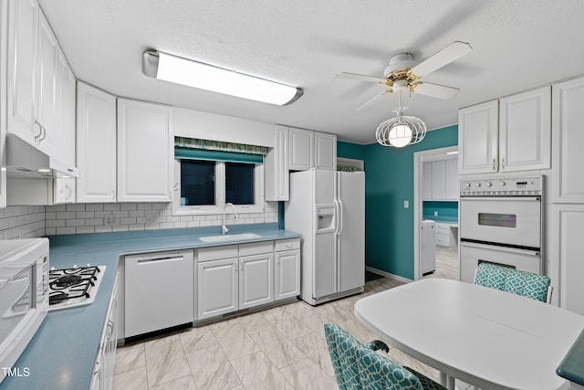 kitchen with white cabinetry, white appliances, under cabinet range hood, and a sink