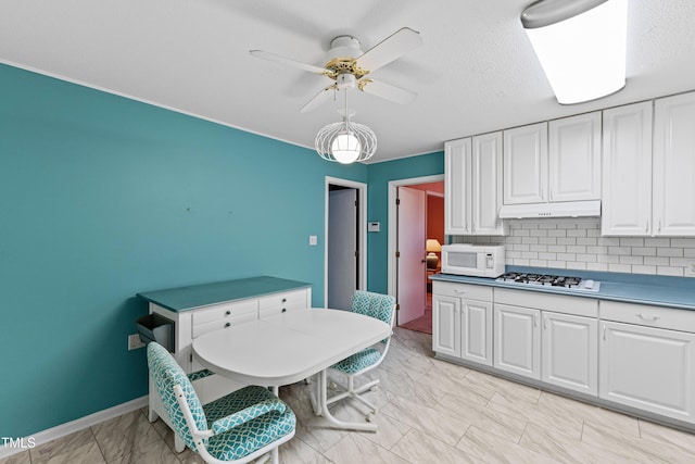 kitchen with under cabinet range hood, marble finish floor, white appliances, and white cabinetry