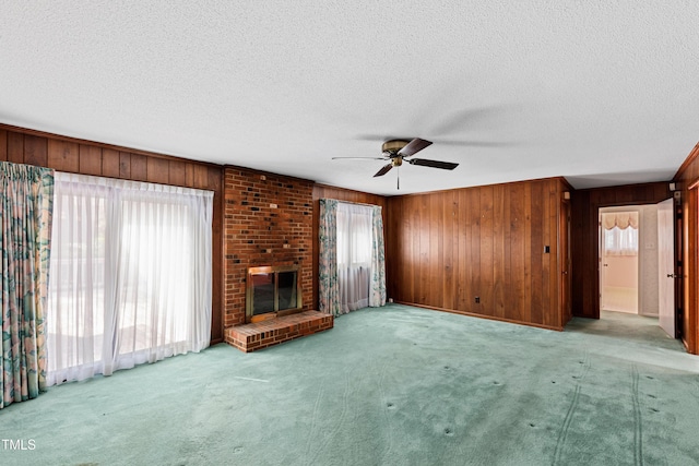 unfurnished living room featuring wooden walls, a brick fireplace, and carpet floors