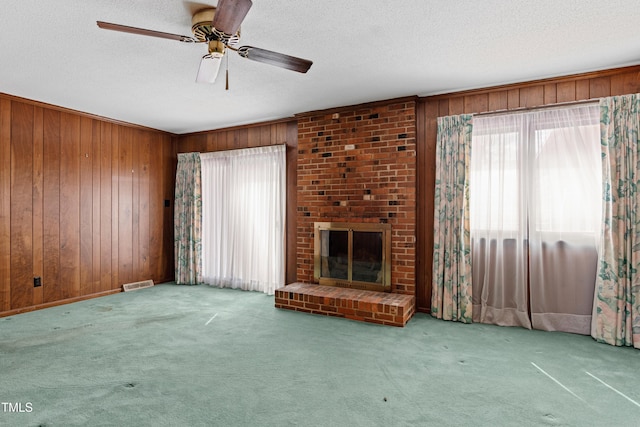 unfurnished living room with visible vents, carpet flooring, a fireplace, and wooden walls