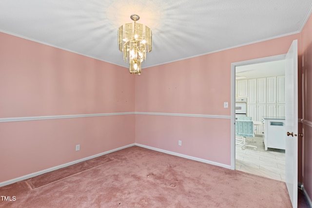 spare room featuring an inviting chandelier, baseboards, carpet floors, and ornamental molding