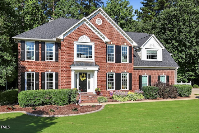 2514 Mcgowan Ct, Wake Forest, NC 27587 - colonial-style house with brick siding, a front yard, roof with shingles, and a chimney
