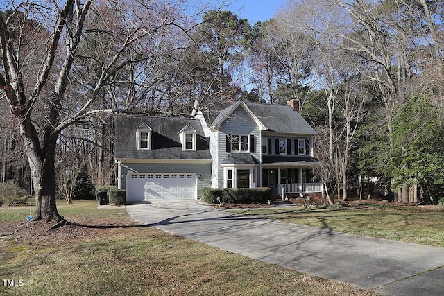 colonial inspired home featuring a garage, a front yard, a porch, and driveway