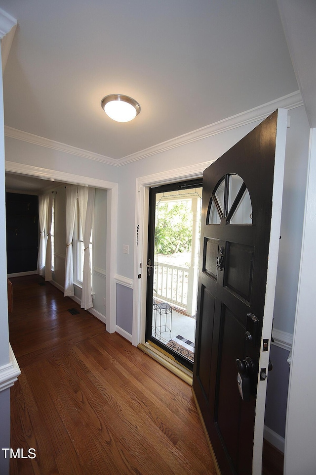 entryway featuring visible vents, baseboards, wood finished floors, and ornamental molding