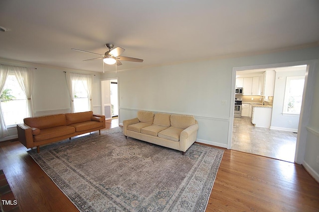 living room with crown molding, baseboards, and wood finished floors